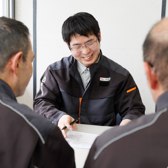 同僚に紙を見せる笑顔の男性スタッフ