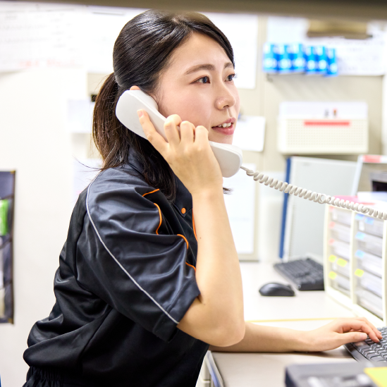 PCデスクで電話対応する女性スタッフ