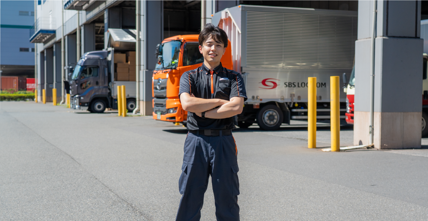 倉庫前で笑顔で立つ男性管理スタッフ