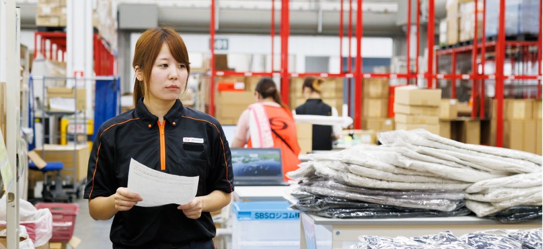 倉庫内荷物の点検を行う女性物流管理スタッフ