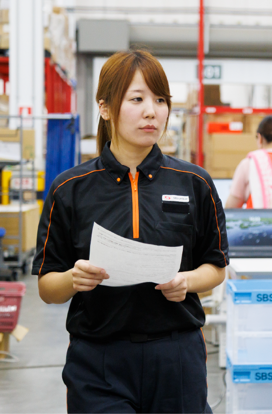 倉庫内荷物の点検を行う女性物流管理スタッフ