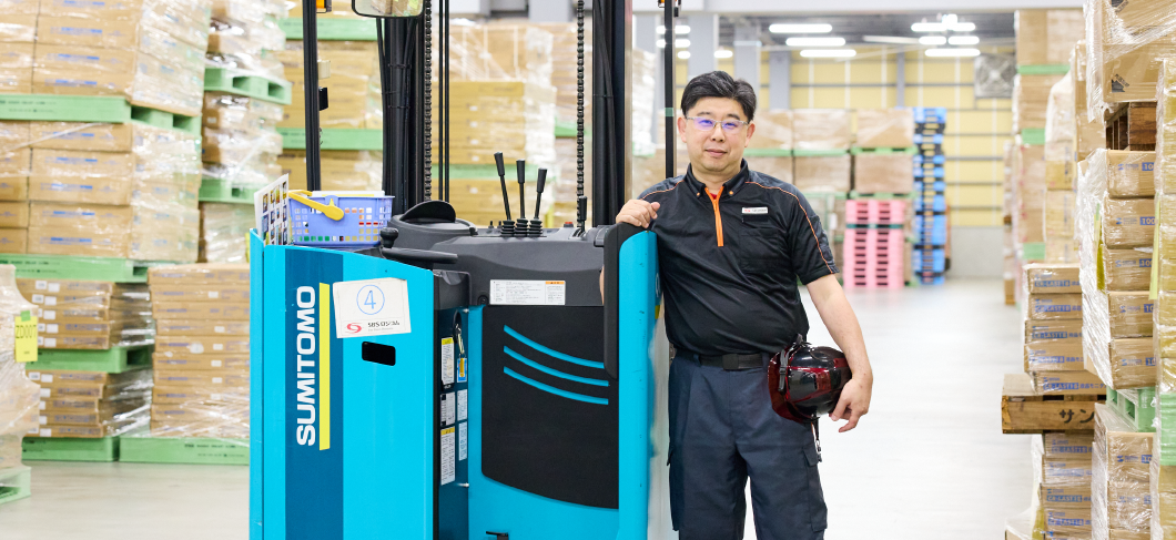 フォークリフトの横に立つ支店長