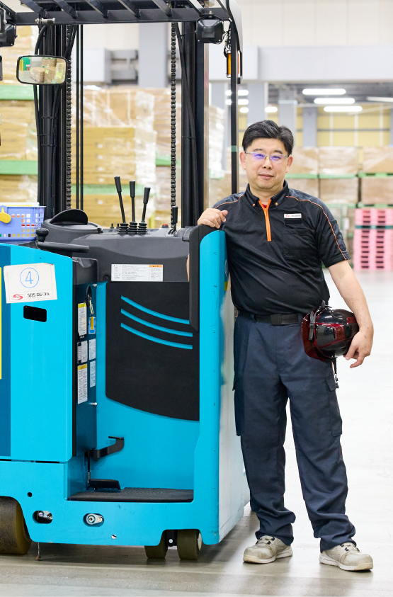 フォークリフトの横に立つ支店長