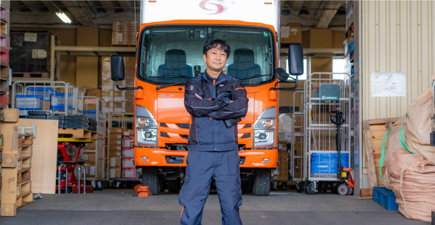 トラックの前に立つ支店長