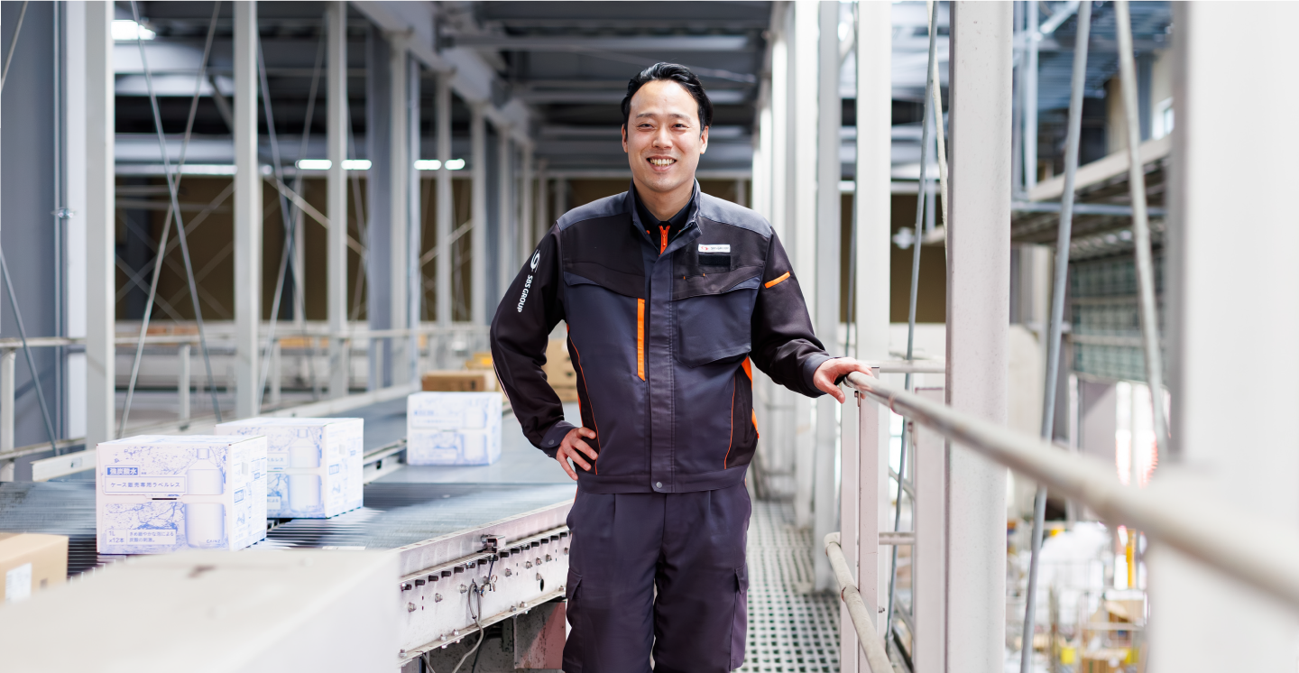コンベアーの前でポーズをとる物流管理スタッフ