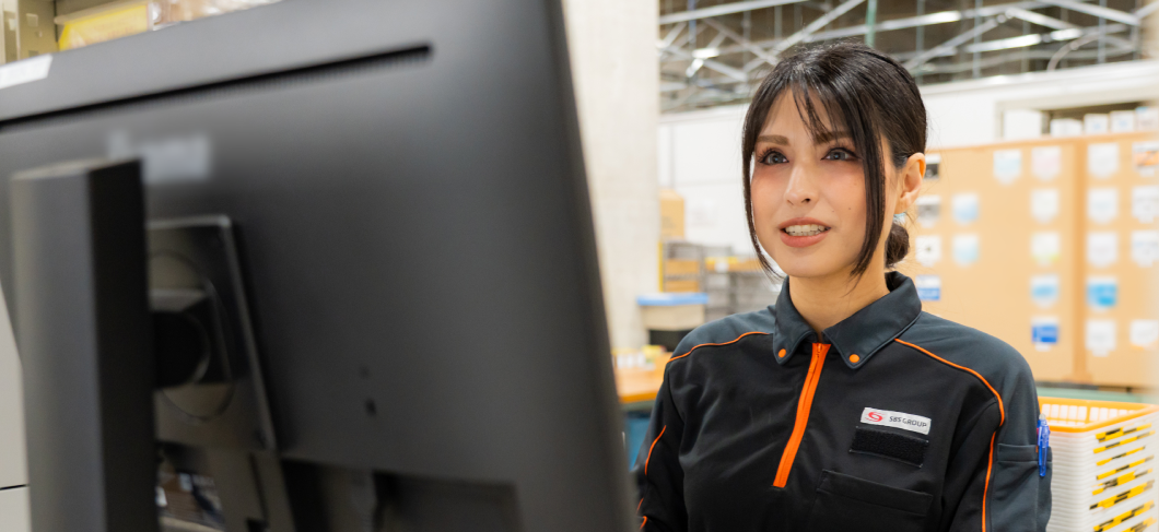 倉庫でPCでチェックする女性スタッフ